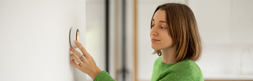Woman adjusting thermostat
